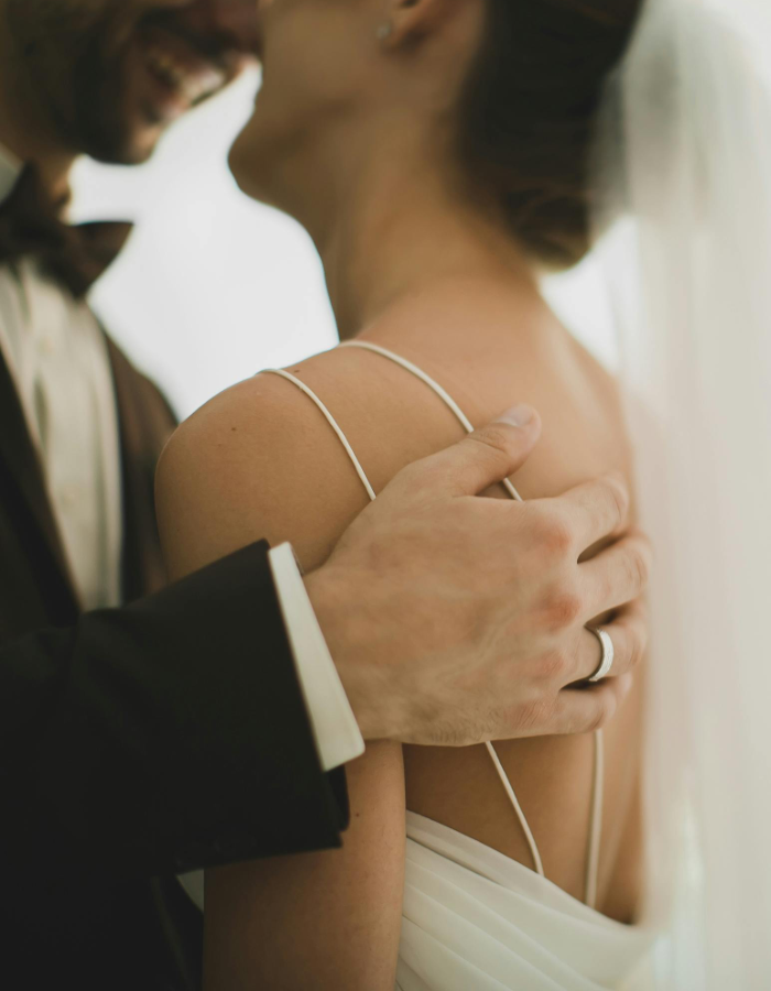 Close-up of a couple embracing with a soft focus background and a focus on the man's wedding band